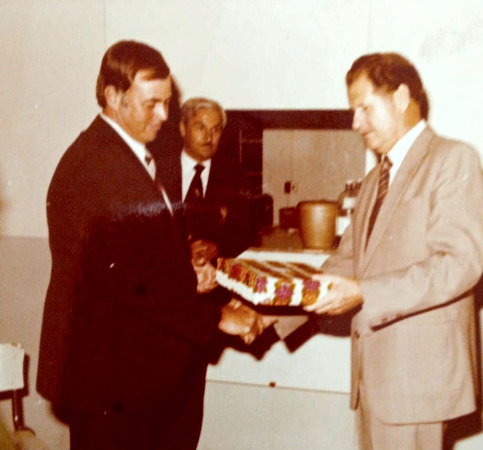 A person in a suit holding a cake

AI-generated content may be incorrect.