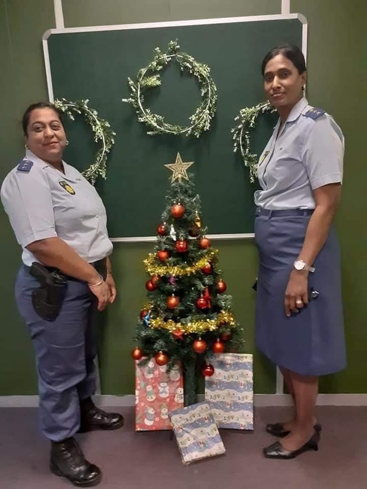 Two women in uniform standing next to a christmas tree AI-generated content may be incorrect.