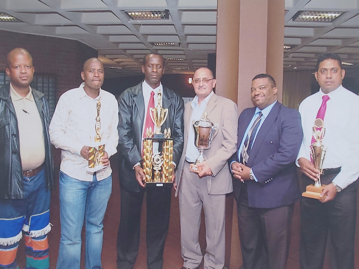 A group of men holding trophies AI-generated content may be incorrect.