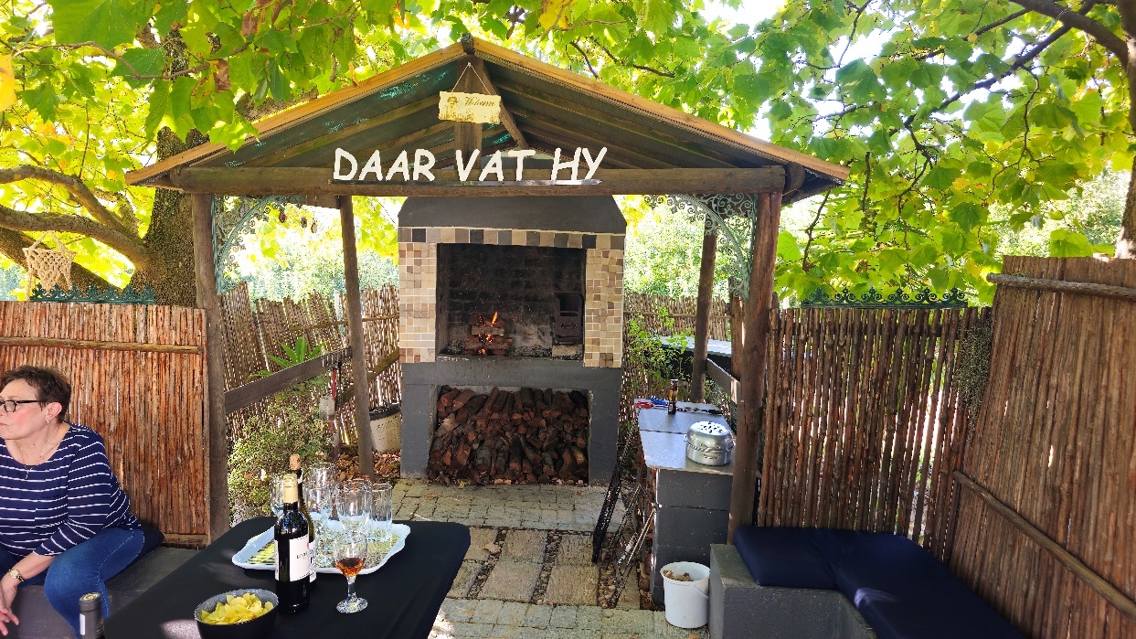 A outdoor grill with a table and a table with a wine bottle AI-generated content may be incorrect.