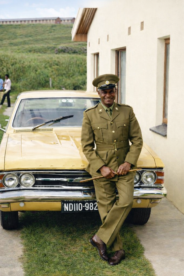 A person in a uniform leaning on a car AI-generated content may be incorrect.
